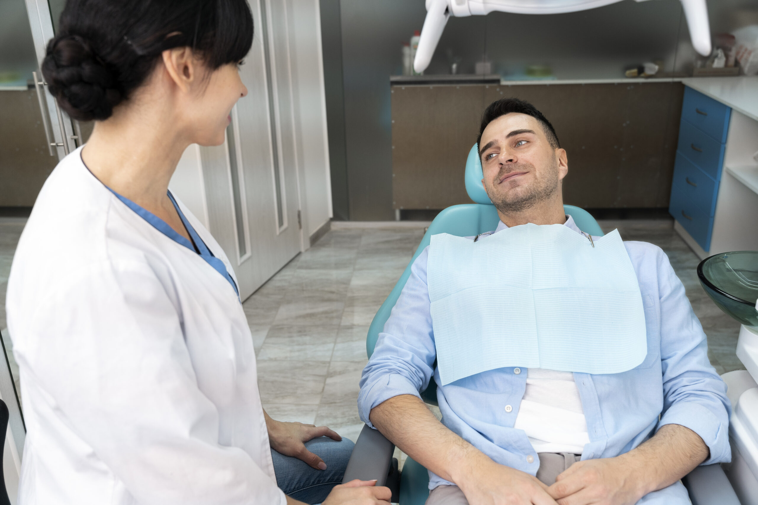 Patient resting in a dental chair after IV sedation while speaking with a dental professional